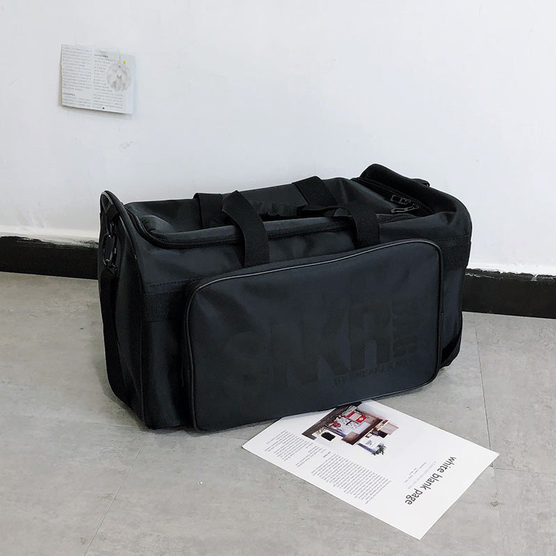 Black duffel bag on a gray floor with a white wall background