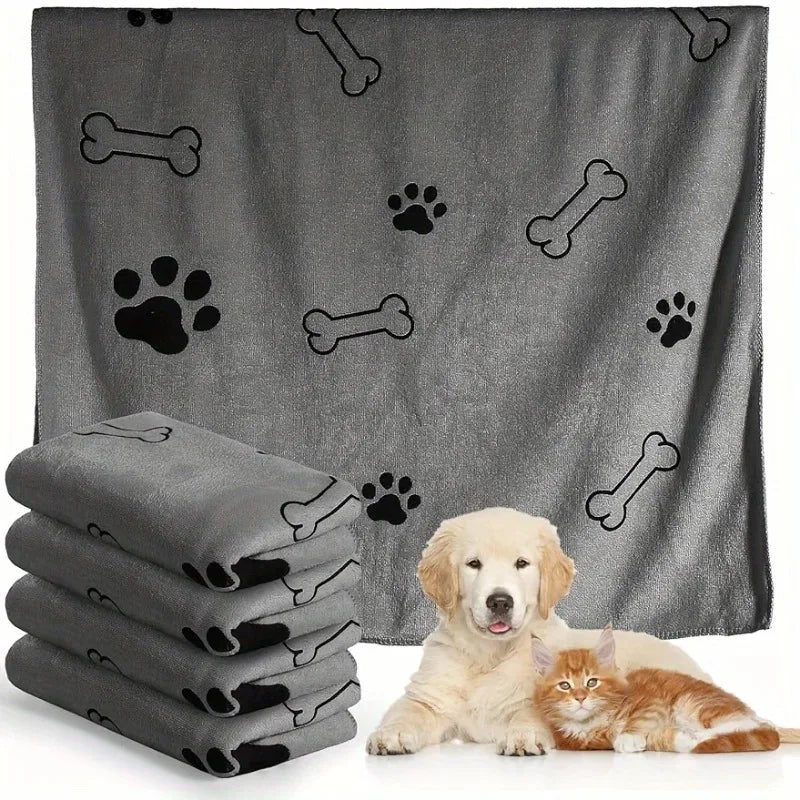 Grey pet towel with bone and paw prints, folded and unfolded, with a dog and cat sitting underneath.
