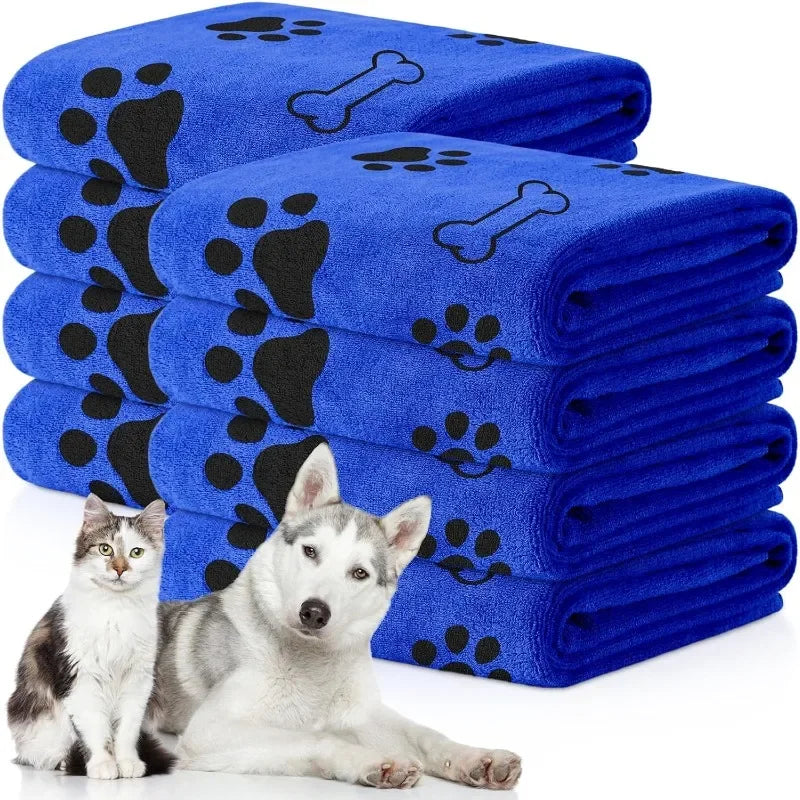 Stack of blue towels with black paw and bone prints, featuring a cat and dog in front.
