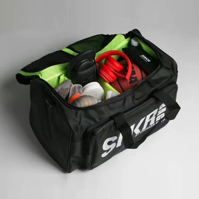Black duffel bag with various items on a gray background