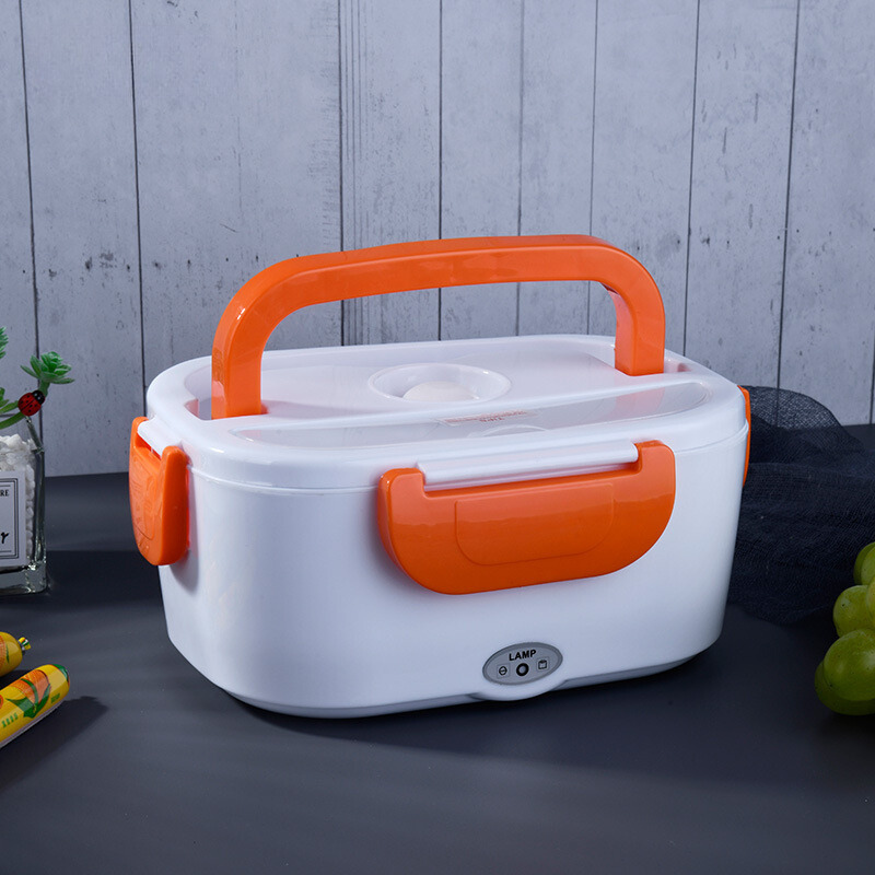 White and orange electric lunch box on a dark surface with a light gray wooden background