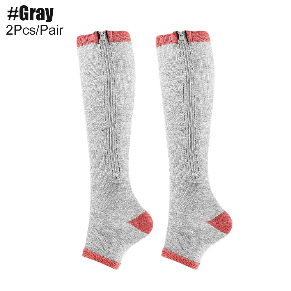 Grey knee-high compression socks with red accents and zippers on a white background